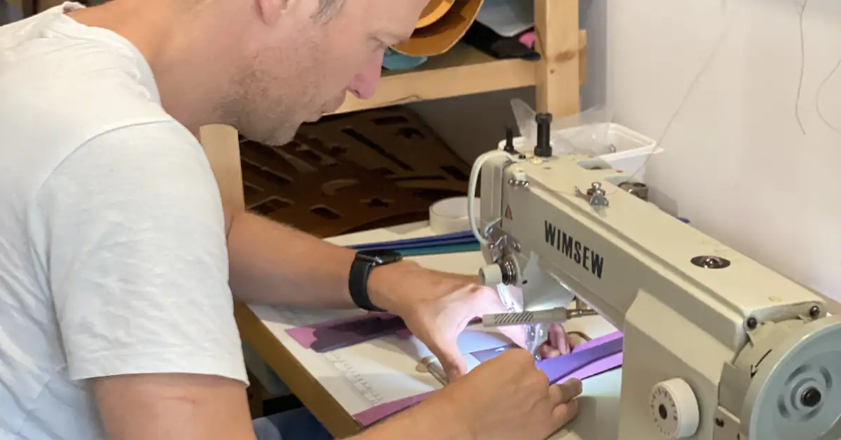 A man sewing a dog collar at a sewing machine in the petiquette workshop