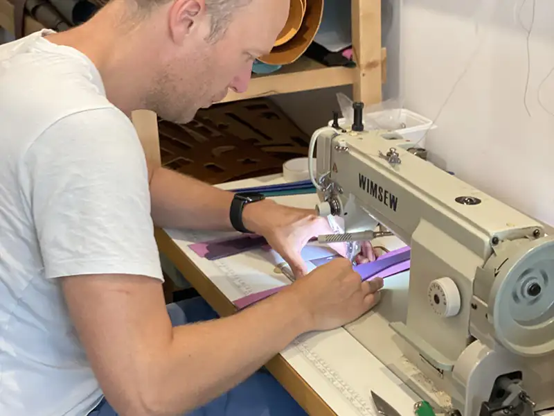 photo of a man sewing a leather dog collar in the petiquette workshop