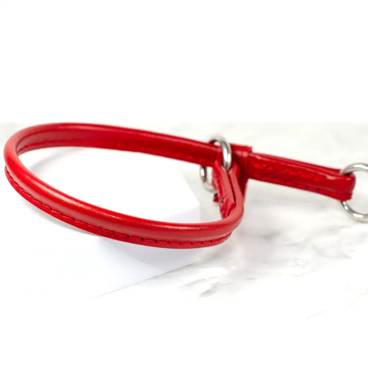 a lightweight red leather dog slip collar with keeper on a white marble surface, made by Petiquette