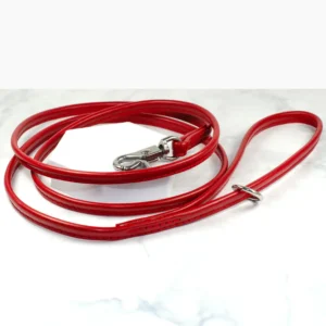 A rounded leather lead in bright red on a white marble background, made by Petiquette