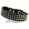 A close-up of a black leather collar in a punk rock style with silver studs and bright red Swarovski crystals, made by Petiquette